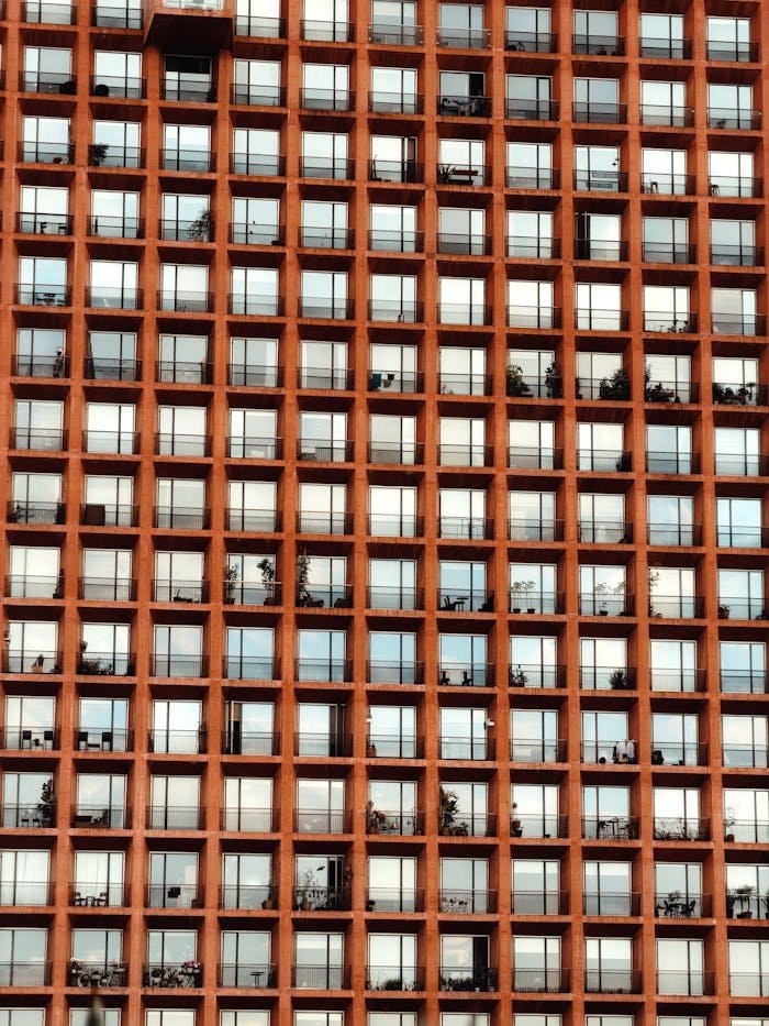 Close-up of a modern building facade with grid-patterned windows and red structure.